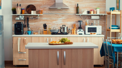 Classic modern kitchen with table in the middle of it, nice wooden details and parquet floor. Dinner room, open space, design luxury arhitecture residential decoration with dining table in the middle