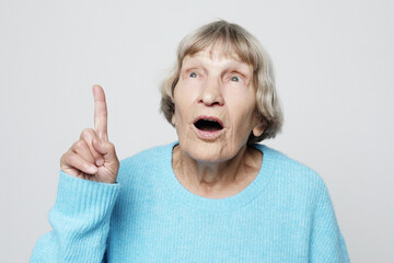 idea, attention and people concept - portrait of smiling elderly woman pointing finger up