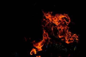 Flame fire on black background. Fire creates infinity shapes when it burns. The orange from the flame and the black backgroud creates interesting textures. Flames from hell. Burning power.