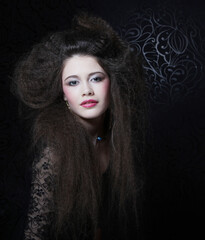 Beautiful young woman with long curly hair and evening make-up wearing black dress and jewerly