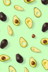 Avocado. Background made from isolated Avocado pieces on green background. Flat lay of fresh ripe avocados and avacado pieces.