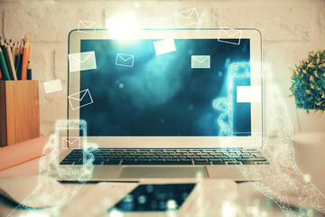 Desktop computer background in office and flying envelops hologram drawing. Double exposure. Electronic mail concept.