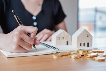 The woman's hand is writing down income and expenses in preparation for her future home purchase.