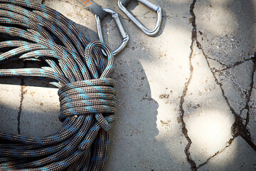 Coiled climbing rope and steel carabiner. Mountain climbing equipment: harness, brakes, quickdraws,...