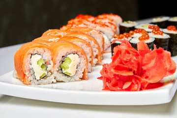 Rolls with salmon and cucumber, cheese and wasabi on a white plate. Closeup, selective focus