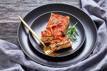Vegan tofu spinach lasagna on a black plate - obrazy, fototapety, plakaty