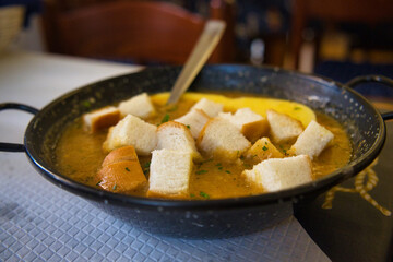 Delicious Italian fish soup with sardines, prawns, shells and bread croutons