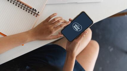Woman hand holding mock up smartphone in workspace