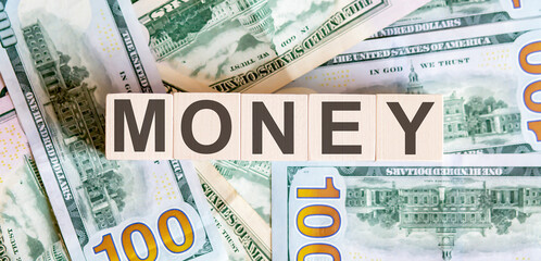 Concept words MONEY on wooden blocks on a beautiful background from dollar bills.