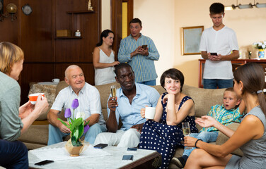 Fototapeta premium Three generations of happy international family blithely talking together in cozy home interior