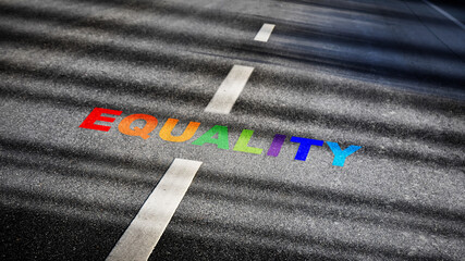 Equality word with white dividing lines on black asphalt road surface with sunlight. Social issue...