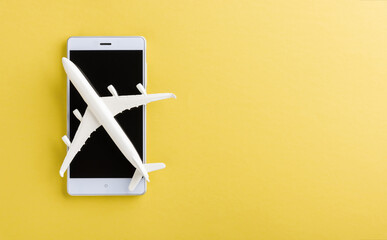 World Tourism Day, Top view flat lay of minimal toy model plane, airplane, and smartphone blank screen, studio shot isolated on a yellow background, accessory flight holiday concept