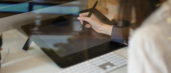 Designer working on her concept with graphic  tablet, view through glass view