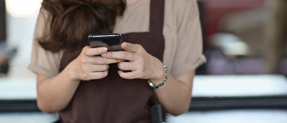 Female barista holding smartphone while taking a break from work