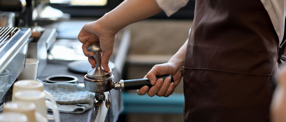 Professional barista grinding coffee in the coffee shop