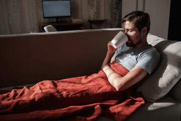 Fototapeta premium Young ill man drinking hot tea at home