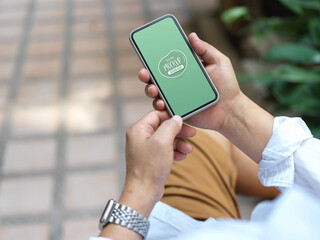 Man holding mock up smartphone while siting outdoor