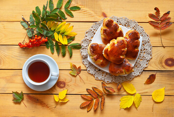 Beautiful autumn still life with freshly baked homemade potato pies in the form of fallen leaves and a cup of tea on a wooden table. Tasty breakfast. Flat lay, close-up, top view