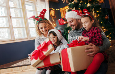 Obraz na płótnie Canvas Family of four celebrating Christmas, exchanging presents 