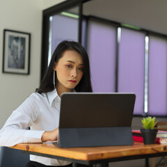 Female office worker working with digital tablet on wooden worktable