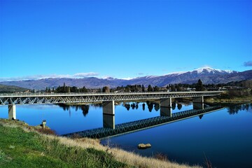 A bridge with blue sky crossing a river on a drive from Queenstown to Christchurch