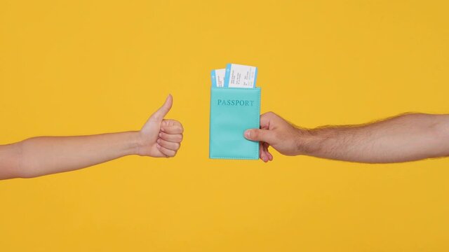 Close up cropped traveler tourist man hands give hold passport ticket plane isolated on yellow background. Passenger traveling abroad to travel on summer weekends getaway. Air flight journey concept