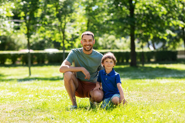 Fototapeta premium family, fatherhood and people concept - happy smiling father with little son at summer park