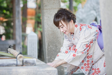 神社でお清めをする浴衣姿の女性
