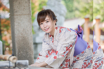 神社でお清めをする浴衣姿の女性
