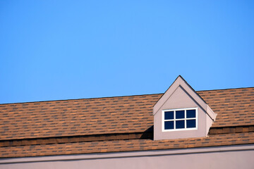 orange roof of the house with white window frame in dark blue clear sky