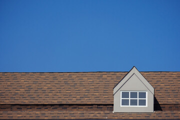 orange roof of the house with white window frame in dark blue clear sky