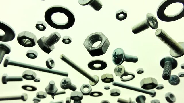 Video showing insulated bolts, nuts and washers passing through in backlight. Galvanized metal fasteners.