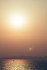 sunset sky at sea with island with flare effect from sun shine