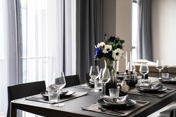 Home Interior with dining room table setting with gold stainless tableware black cutlery setting on natural wood top / interior design
