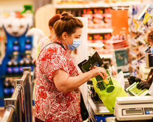 Elderly woman wearing facial mask from coronavirus covid-19 and shopping at grocery store.