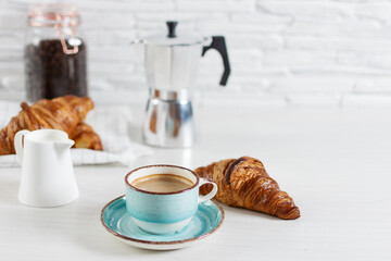 A cup of coffee and ingredients and equipment for making coffee on kitchen table.