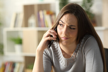Suspicious woman calling on phone sitting at home