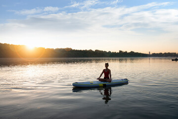 Woman meditating and practising yoga during sunrise