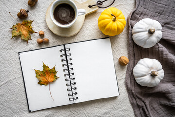Ein unbeschriebenes Notizbuch, eine Tasse Kaffee, Kürbis und Herbst Dekoration auf einem Tisch. Flat lay, Retrostil.