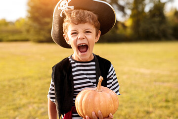 Little pirate holding pumpkin in park
