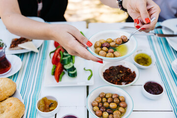 a woman is holding green olive at Turkish Breakfast table
