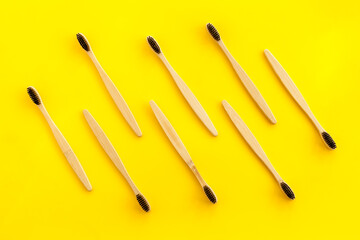 Eco materials concept with bamboo tooth brush on yellow background top view copy space