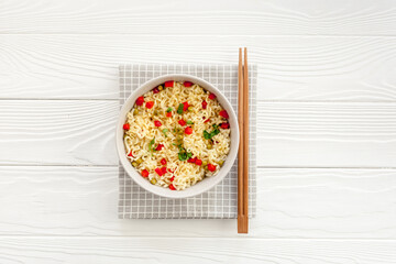Instant noodle with pepper,peas and greens. White wooden background top view copy space