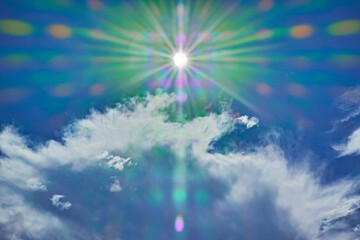 Fototapeta na wymiar 派手にゴーストが出るカメラで撮った中央上部に太陽を入れた雲のある青空