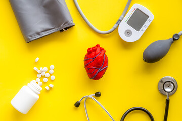 Heart and treatment. Heart near pills tonometer, treatment  on yellow background top view