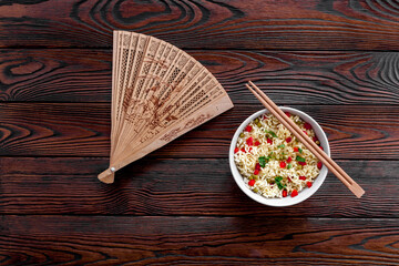 Instant noodle with pepper,peas, chopstick and greens. Dark wooden background top view copy space