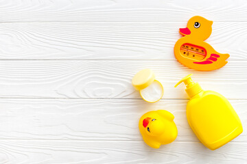Bath accessories for kids. Yellow rubber duck,towel, cream, shampoo on white wooden background top view