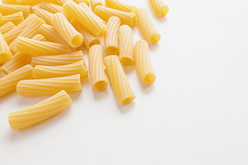 Bunch of raw macherroni pasta spread on white background, copy space