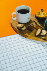 Fototapeta na wymiar Cup of coffee espresso or cappuccino, wooden cuts, green candle, cinnamon and mushroom on wooden tray on vibrant orange and white background. Fashion stylish and trendy autumn decor composition.
