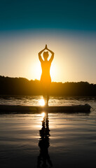 Woman meditating and practising yoga during sunrise